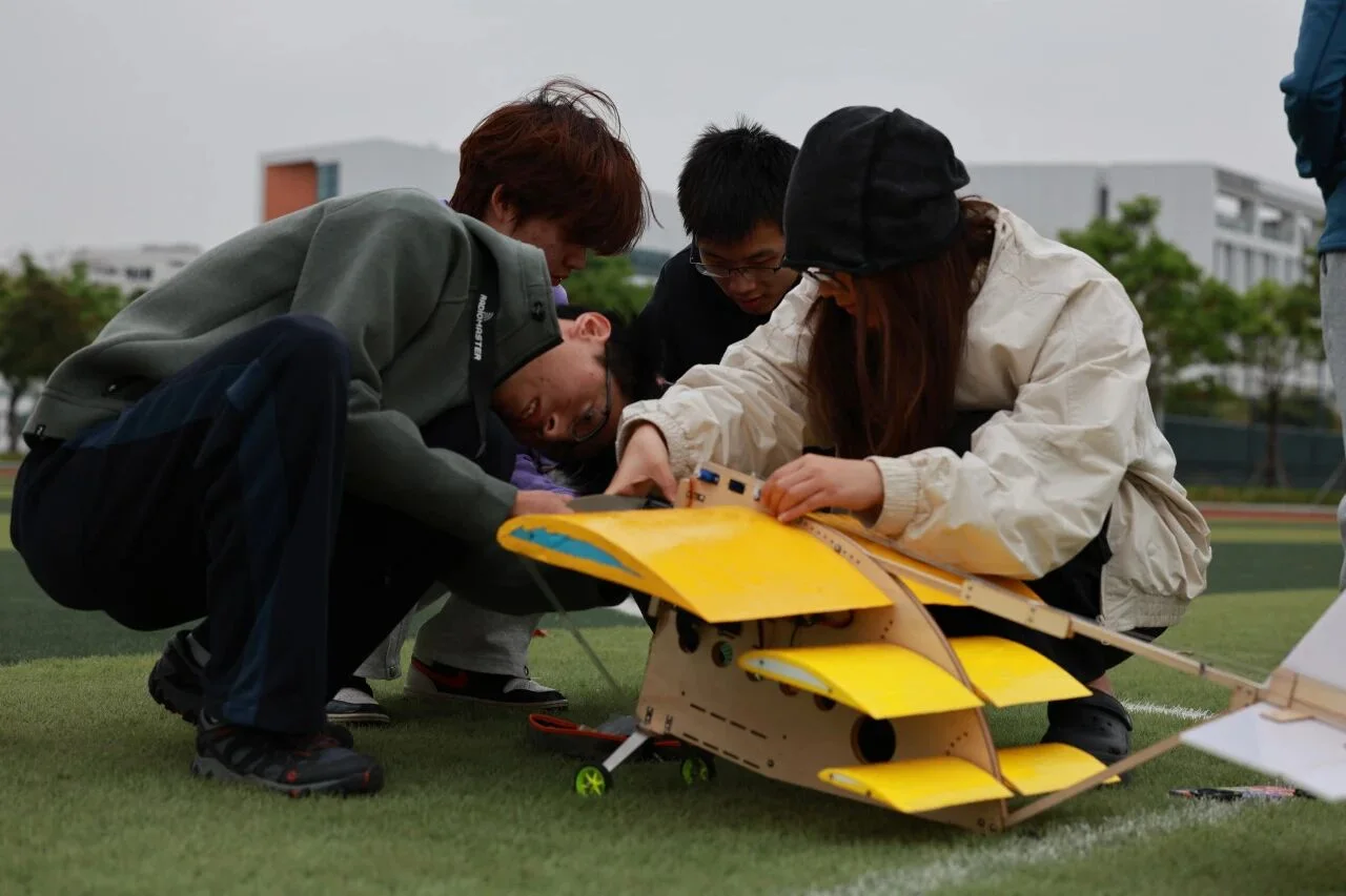 Team members assembling the yellow stacked triple-wing first-generation aircraft